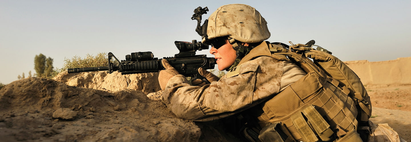 A soldier pointing and looking through the scope of a sniper rifle 