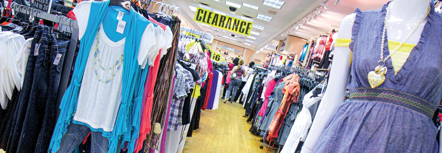 Racks and racks of clothes with a clearance sign hanging from the ceiling
