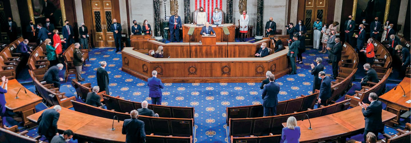 Congresspeople standing in a large circular room with a podium in the front