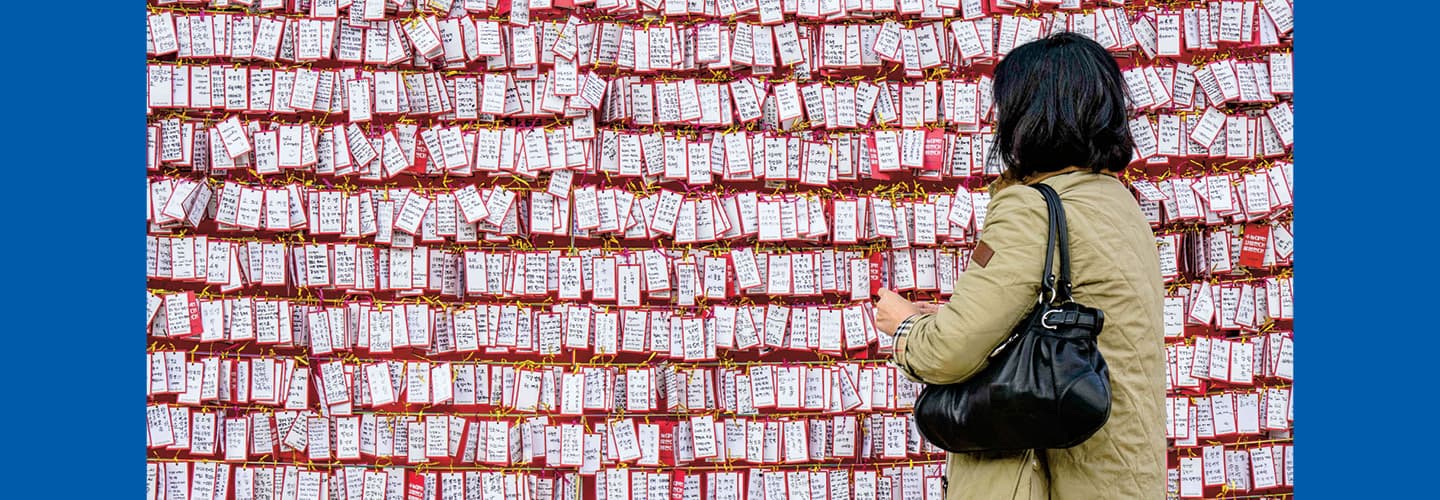 Photo of a person in front of a large wall of prayer notes
