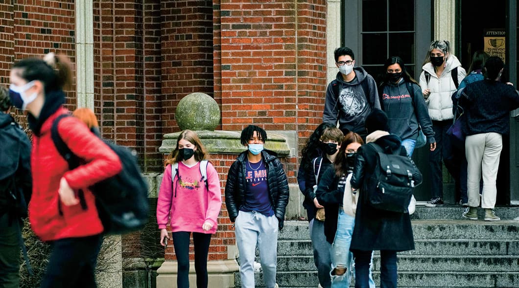Photo of students walking out of school and wearing masks