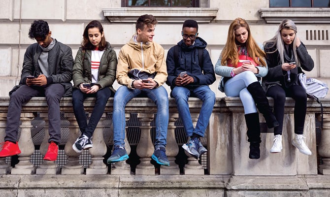 Enlargeable photo of students sitting together and all using their phones
