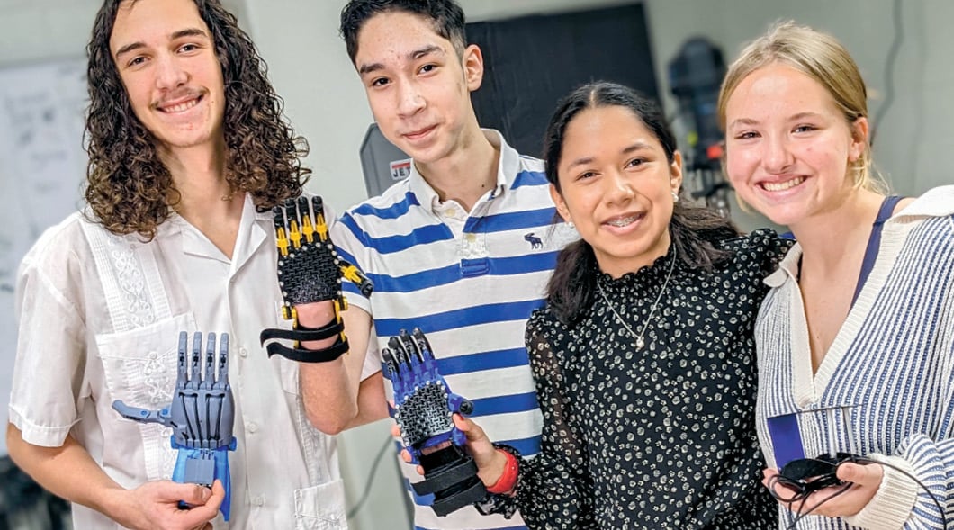 Photo of four students posing with robotic hands