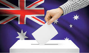 Hand putting a ballot in a box against a backdrop of the Australian flag