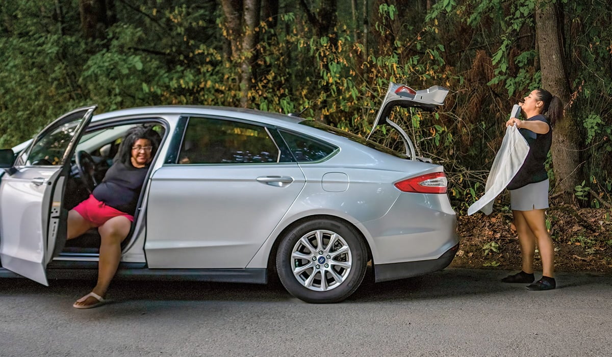 Photo of two people and the small car they live in
