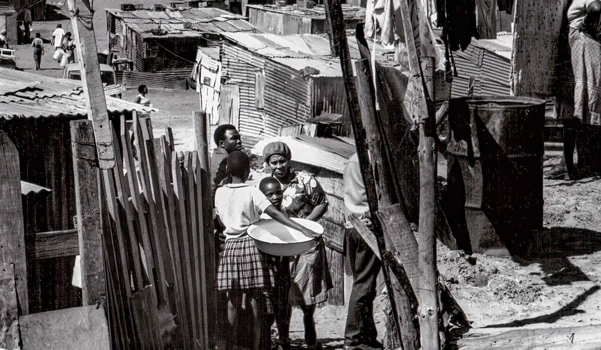 Black & white photo of people living in a poverty-stricken community