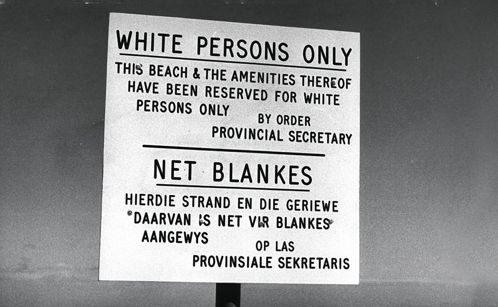 Black & white photo of a beach sign that says, "White Persons Only"