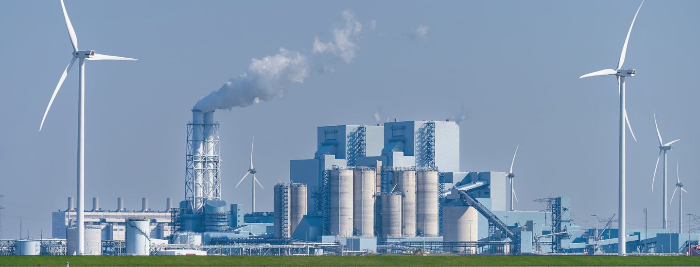 Image of wind turbines with polluting factories in background