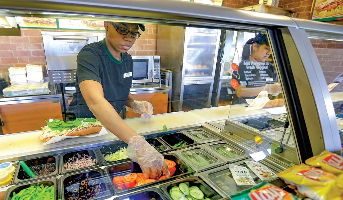 Image of a worker at subway making a sandiwch