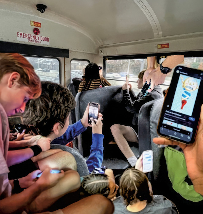 Image of students using their phones while on school bus