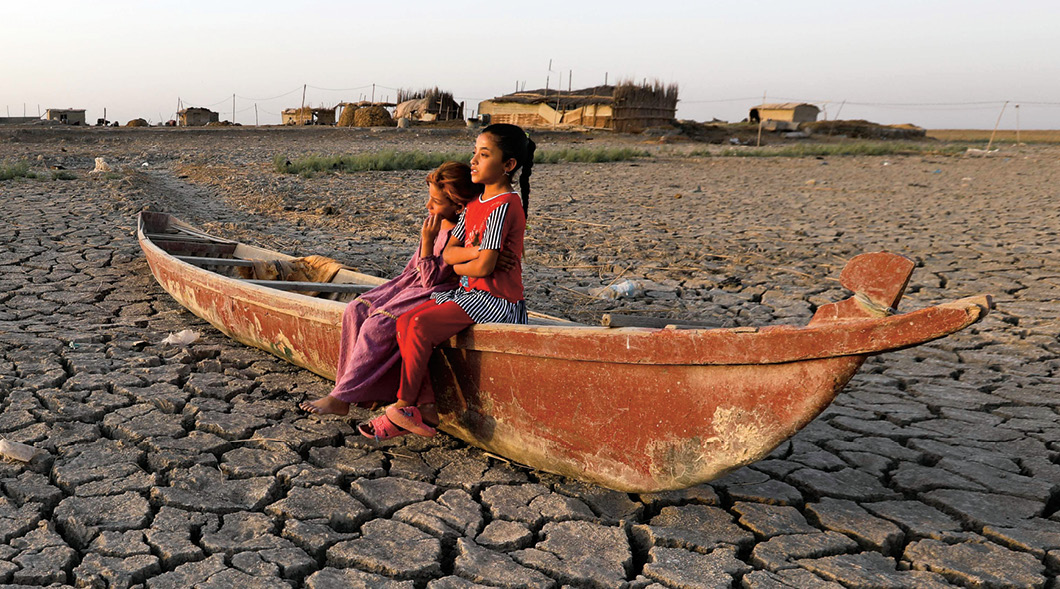 Image of two people sitting on a boat in a dried up river