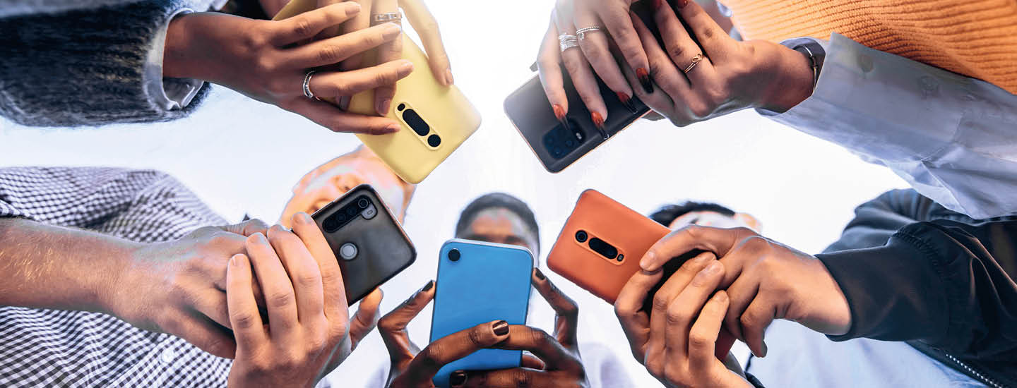 Photo of five people crowded in a circle and all using their phones