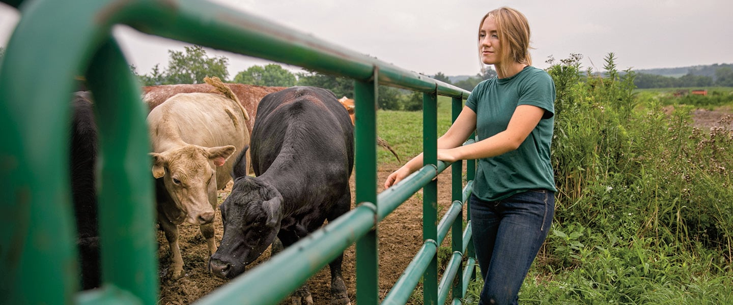 Photo of a teen farmer posing with cows