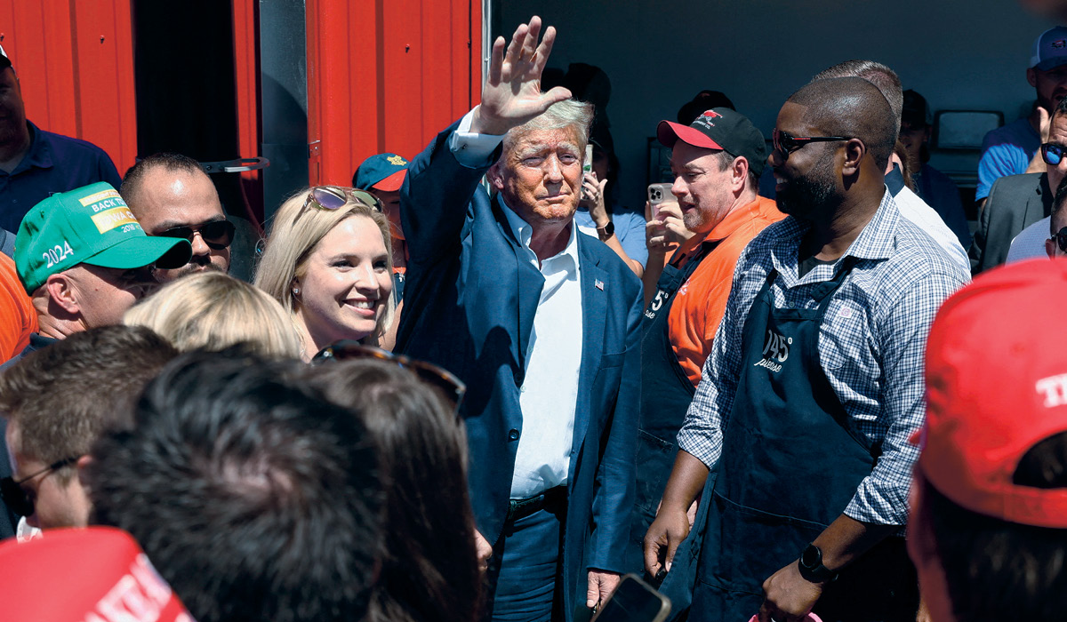 Image of people surrounding Trump who is waving and smiling