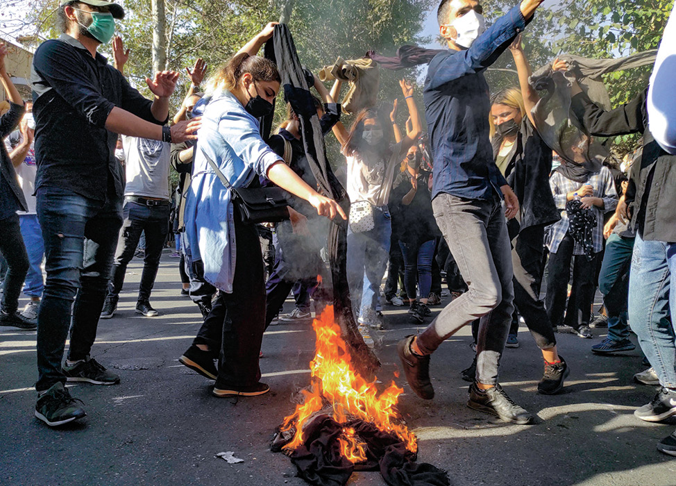 Photo of people in a crowd burning hijabs