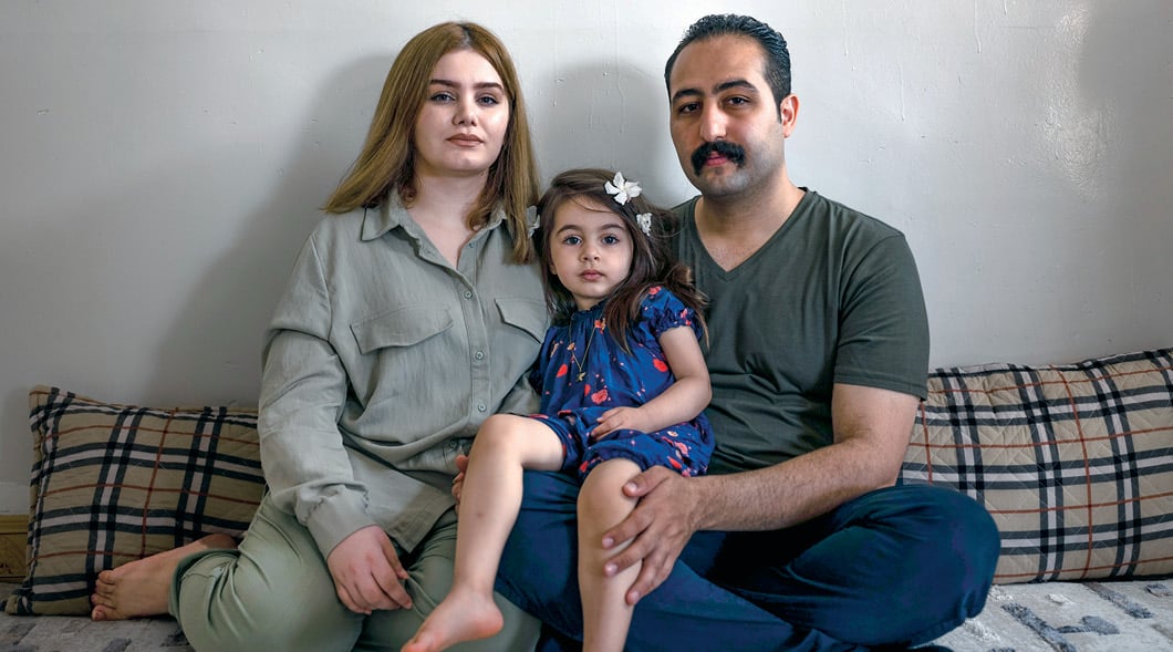 Photo of an Iranian family of three sitting on the couch