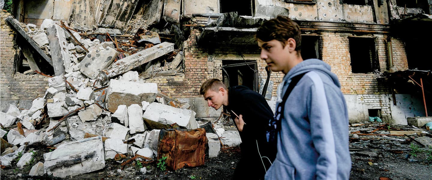 Photo of two people walking by destroyed buildings
