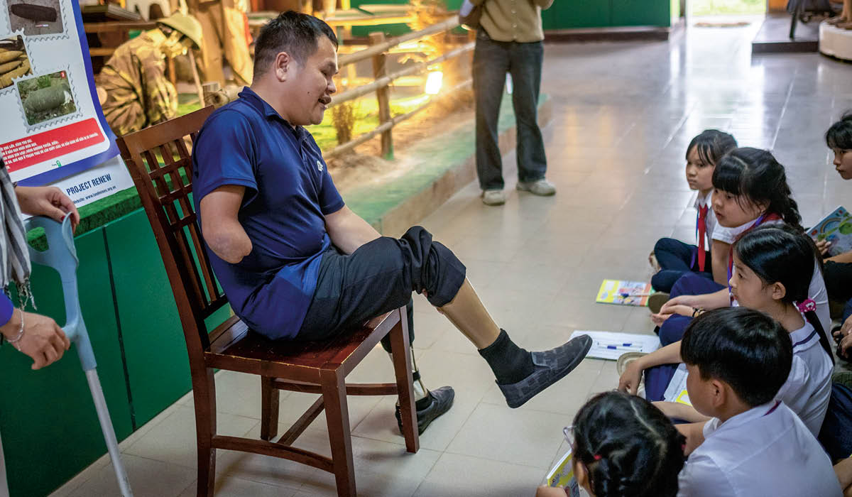 Photo of a soldier showing group of students his two prosthetic legs