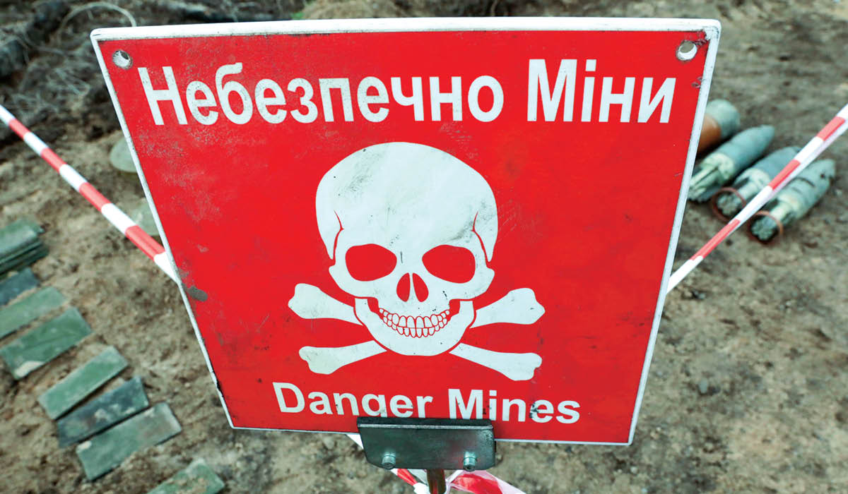Image of a sign in both English & Vietnamese with skull & cross bones, "Danger Mines"