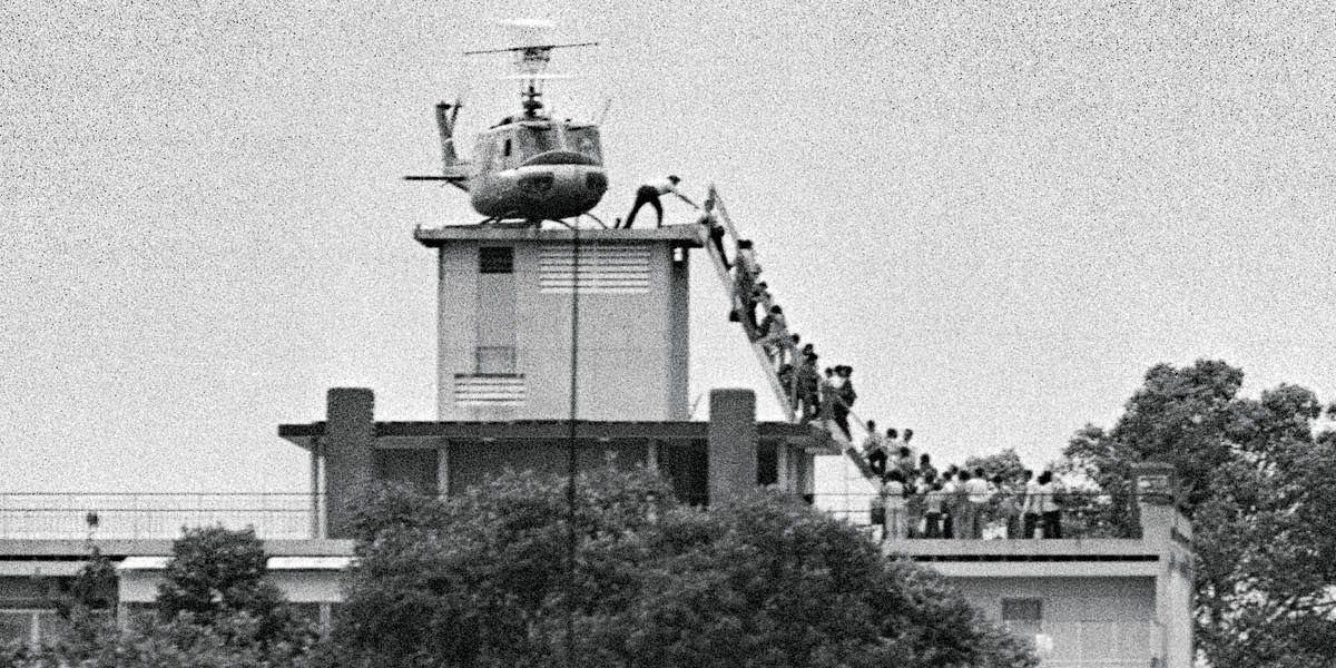 Black & white photo of a long line of people boarding helicopter