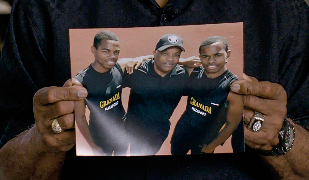 a man&apos;s hand hold up a photo of him hugging his two sons