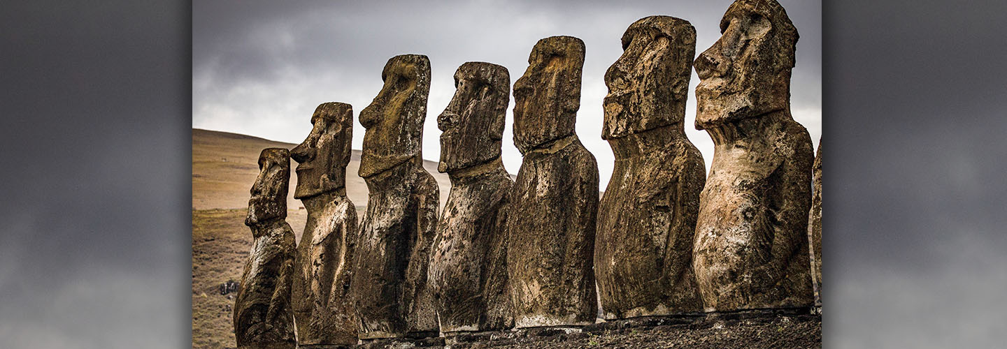 Seven moai statues standing in a row on Easter Island against a cloudy sky