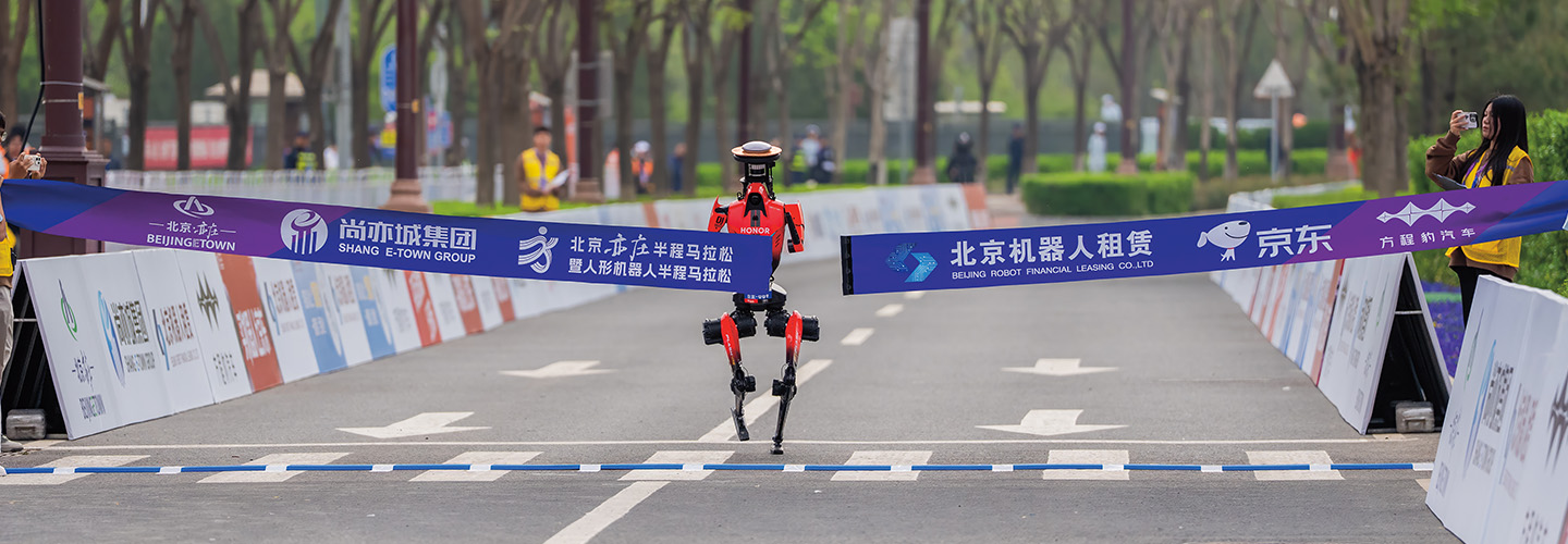 A humanoid robot crosses a finish line banner at the Beijing half marathon robot race